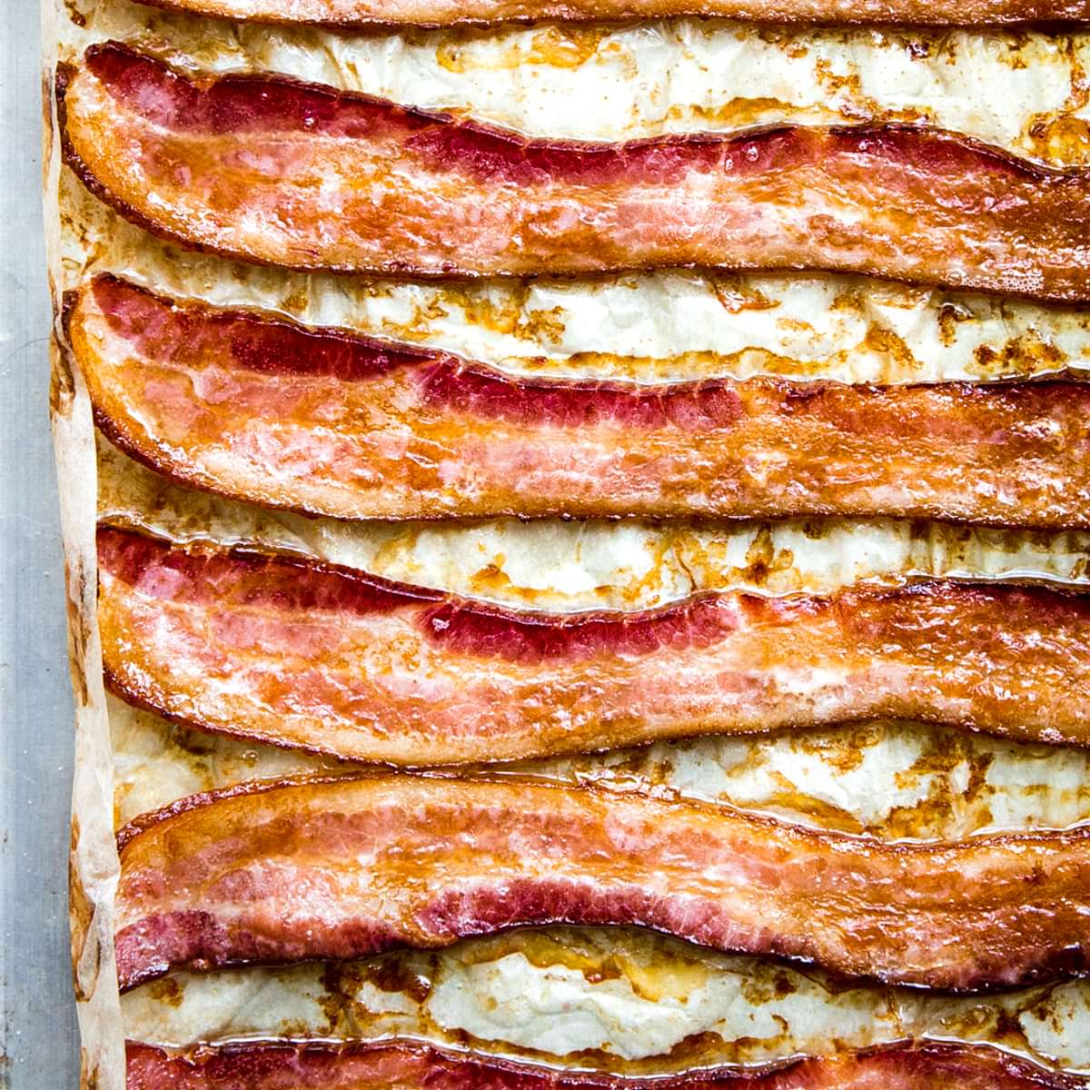 Oven-baked bacon on a parchment lined baking sheet, fresh from the oven and perfectly crispy.