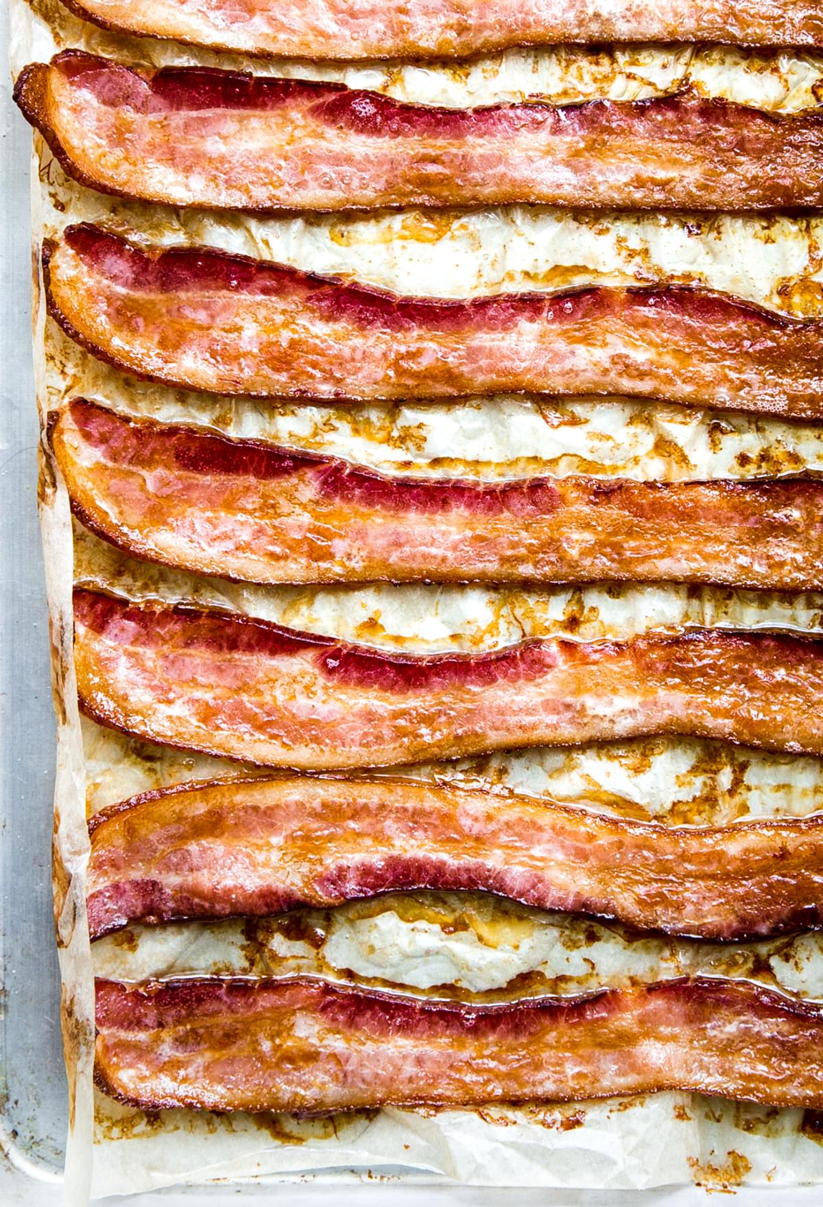 Oven-baked bacon on a parchment lined baking sheet, fresh from the oven and perfectly crispy.