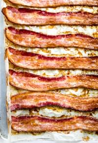 Oven-baked bacon on a parchment lined baking sheet, fresh from the oven and perfectly crispy.