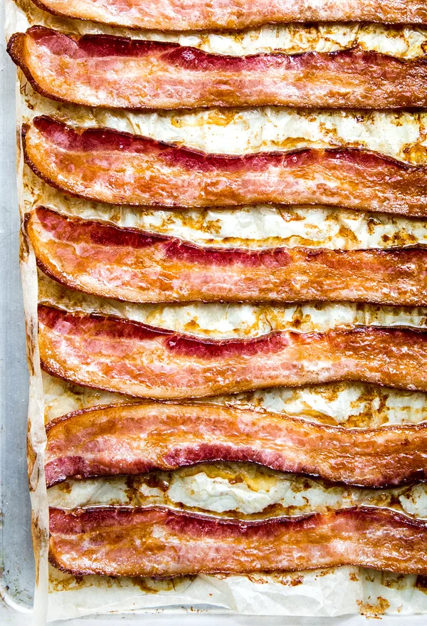 Oven-baked bacon on a parchment lined baking sheet, fresh from the oven and perfectly crispy.