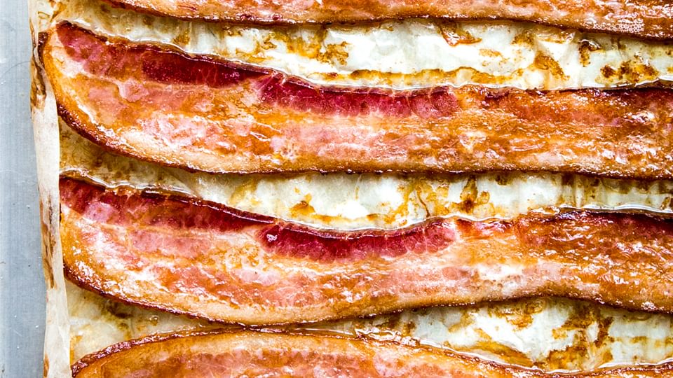 Oven-baked bacon on a parchment lined baking sheet, fresh from the oven and perfectly crispy.