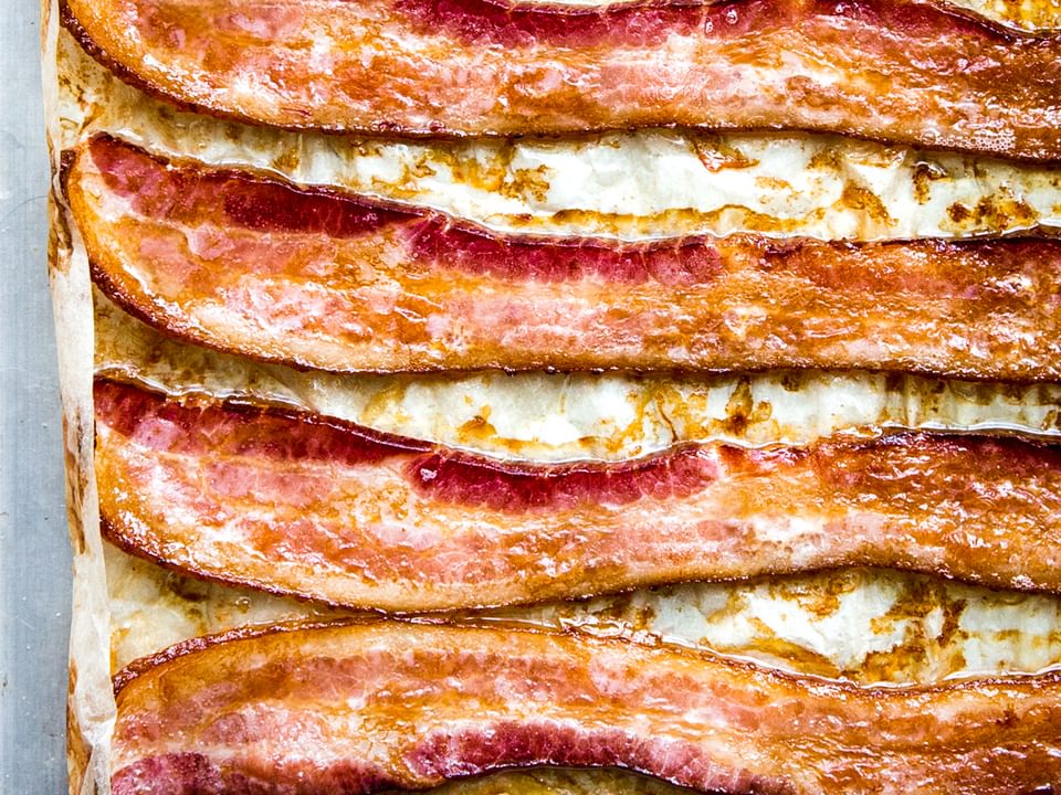 Oven-baked bacon on a parchment lined baking sheet, fresh from the oven and perfectly crispy.