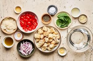 shallots, bread, olive oil, spices, basil, tomatoes and Parmesan in prep bowls to make Panzanella
