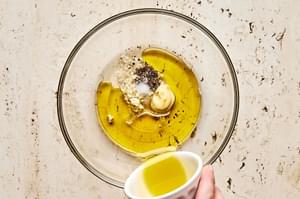 olive oil, honey, vinegar, garlic, mustard, salt, and pepper in a glass bowl