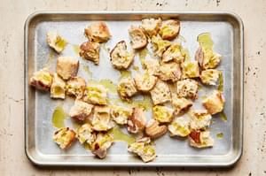 cut up bread tossed with olive oil, salt and garlic powder on a baking sheet