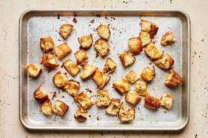 baked cut up bread tossed with olive oil, salt and garlic powder on a baking sheet