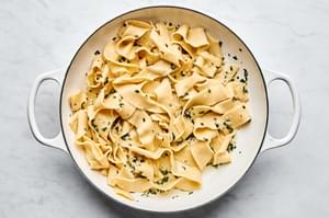 a pot of homemade pappardelle pasta topped with garlicky butter and fresh herb sauce