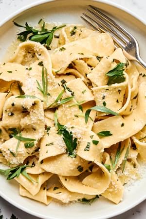 a plate of homemade pappardelle pasta topped with garlicky butter and fresh herb sauce