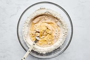 flour, olive oil, salt and eggs being combined with a fork in a large glass bowl