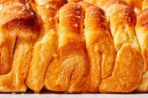 baked homemade parker house rolls on a baking sheet brushed with melted butter and sprinkled with flaky salt