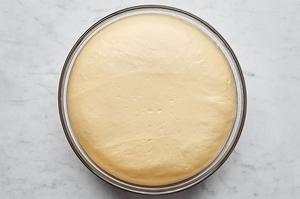 parker house rolls dough rising in a glass mixing bowl