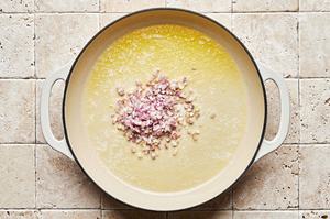 chicken stock, butter and shallots being cooked together in a pot for parmesan risotto
