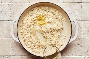 wine being poured into a pot with chicken stock, butter, shallots, garlic, arborio rice, lemon juice and lemon zest