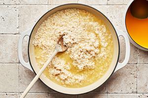 wine, chicken stock, butter, shallots, garlic, arborio rice, lemon juice and lemon zest being cooked in a pot for risotto