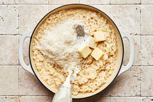 cream, butter, parmesan, salt and pepper being added to a pot with the other ingredients for making parmesan risotto