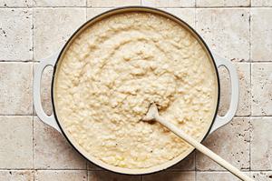 a pot of homemade parmesan risotto being stirred with a wooden spoon