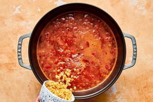 onion, carrot, garlic, tomato sauce, diced tomatoes, chicken stock, spices, water and pasta noodles cooking in a pot