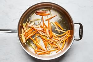 sliced carrots being cooked in a skillet