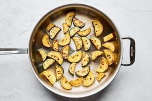 sliced zucchini being cooked in a skillet