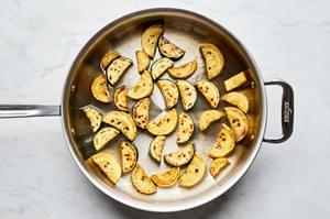 sliced zucchini being cooked in a skillet