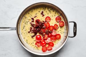 Parmesan, milk, dried basil, garlic powder, salt, pepper, sun dried tomatoes and cherry tomatoes in a skillet