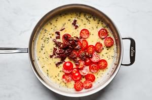 Parmesan, milk, dried basil, garlic powder, salt, pepper, sun dried tomatoes and cherry tomatoes in a skillet