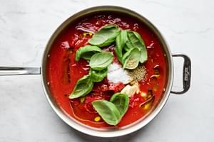 Authentic Italian tomato sauce cooking: San Marzano tomatoes simmering with garlic, herbs & EVOO for homemade pasta sauce