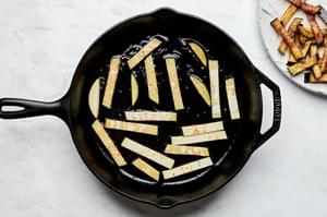 Pan-fried eggplant preparation: Golden aubergine slices cooking in olive oil for traditional Pasta alla Norma