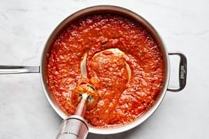 Homemade marinara technique: Blending San Marzano tomato sauce with immersion blender for silky Sicilian pasta