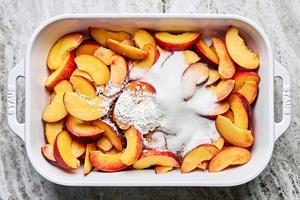 sliced peaches being tossed with sugar, cornstarch, vanilla & almond extract