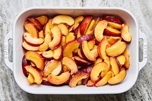 sliced peaches tossed with sugar, cornstarch, vanilla & almond extract in a baking dish