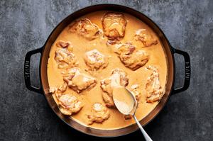 chicken being cooked in a skillet with homemade peanut sauce