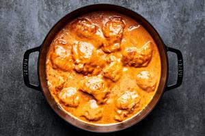 chicken being cooked in a skillet with homemade peanut sauce