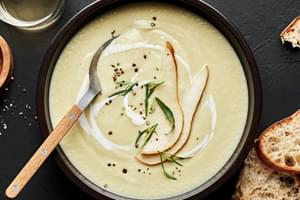 a bowl of pear and buttermilk bisque sprinkled with salt, pepper & tarragon with a pear slice garnish on top
