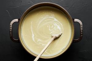 buttermilk being stirred into pear and buttermilk bisque in a pot