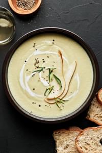a bowl of pear and buttermilk bisque sprinkled with salt, pepper & tarragon with a pear slice garnish on top