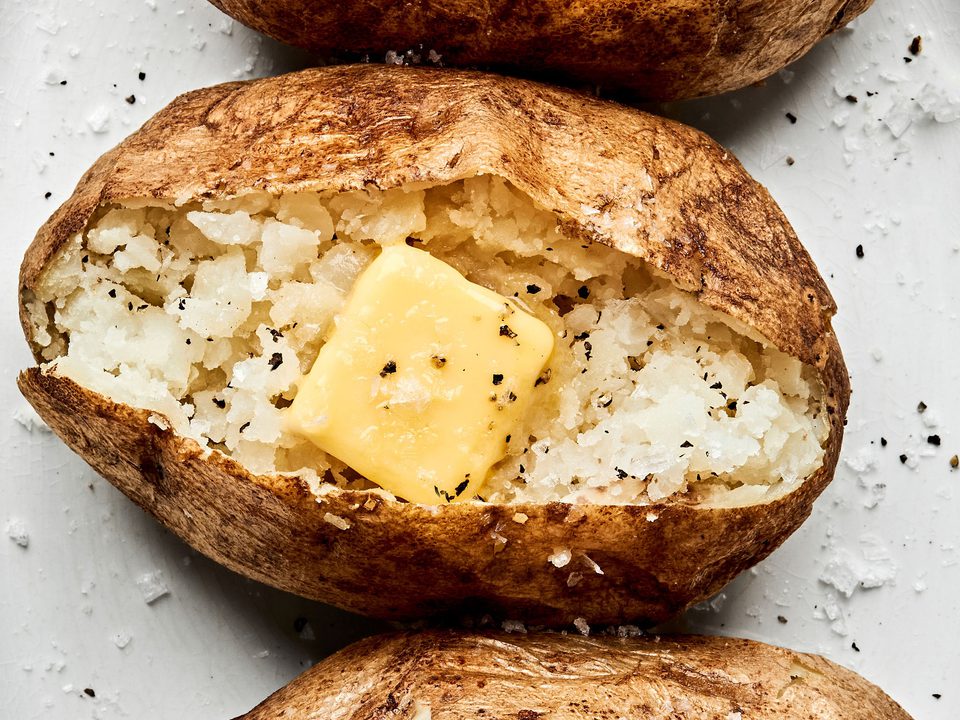 perfect baked potatoes cut open and topped with butter, salt and pepper
