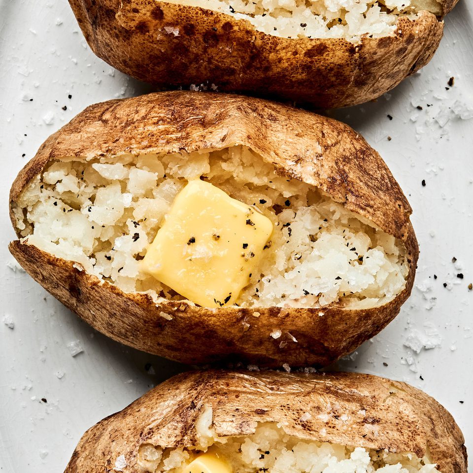 perfect baked potatoes cut open and topped with butter, salt and pepper