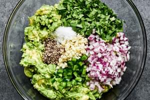 avocados, garlic, pepper, cilantro, jalapeño, red onion, limes and salt in a glass bowl