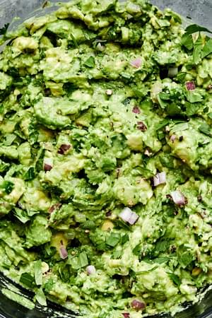 guacamole made with avocados, garlic, pepper, cilantro, jalapeño, red onion, limes and salt in prep bowls to make guacamole