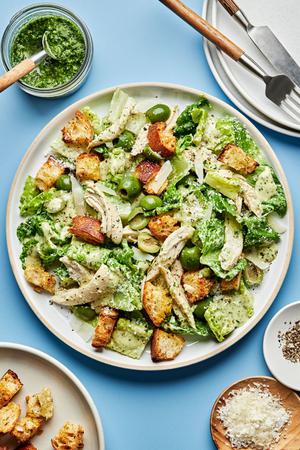 Pesto Caesar Salad with castelvetrano Olives, shredded chicken, parmesan and homemade croutons on a plate