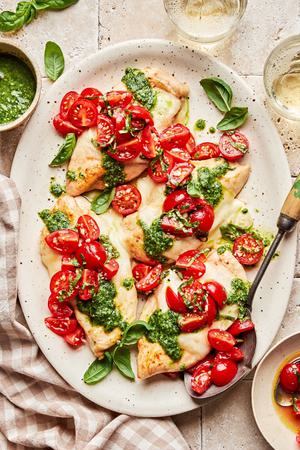Pesto chicken bruschetta on a serving platter. Chicken topped with melted mozzarella, pesto and bruschetta.