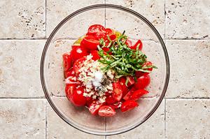 halved cherry tomatoes, garlic, salt, pepper, olive oil, vinegar, lemon juice, and basil in a glass bowl