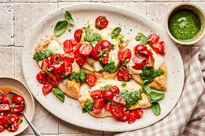 Pesto chicken bruschetta on a serving platter. Chicken topped with melted mozzarella, pesto and bruschetta.