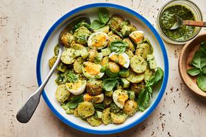 pesto potato salad in a serving bowl made with potatoes, eggs, cucumbers and fresh basil