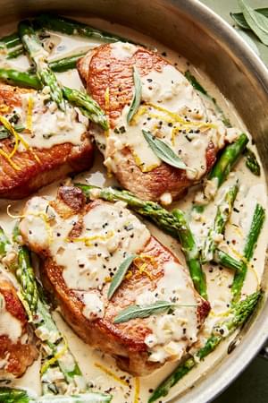 homemade Pork Chops with Asparagus and a Lemon Sage Cream Sauce in a skillet