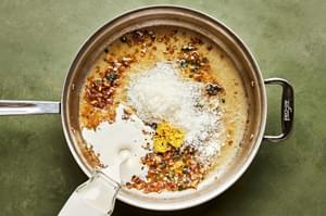butter, shallot, garlic, sage, heavy cream, chicken stock, parmesan, lemon zest, lemon juice and pepper cooking in a skillet