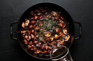 white wine being poured into a skillet with mushrooms, garlic, butter and thyme