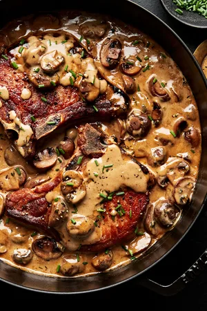 pork chops with mushroom cream sauce in a skillet