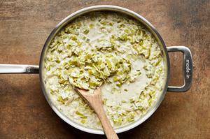 leeks, butter, milk, cream, blue cheese, garlic, mustard, nutmeg, salt, and pepper being stirred in a skillet